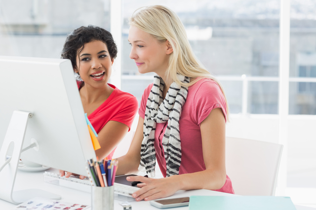 Smiling female business colleagues using computer in a bright office