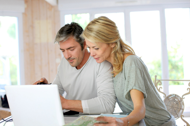 Mature couple planning vacation trip with map and laptop