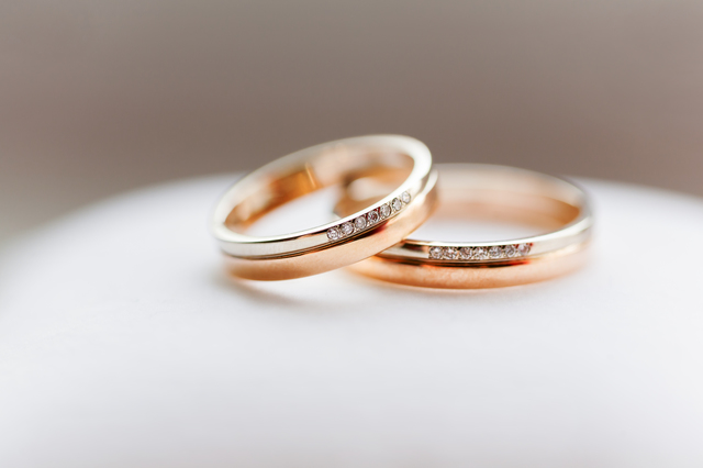 Golden wedding rings with diamonds on white background. Symbol o